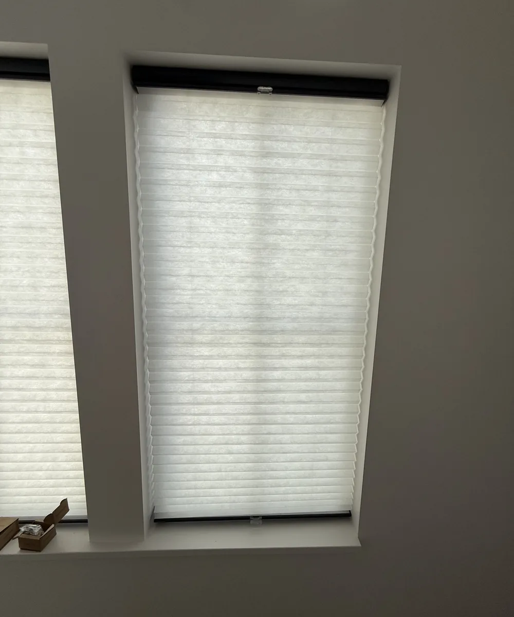 Cordless cellular shade lowered over a bedroom window on a bright afternoon