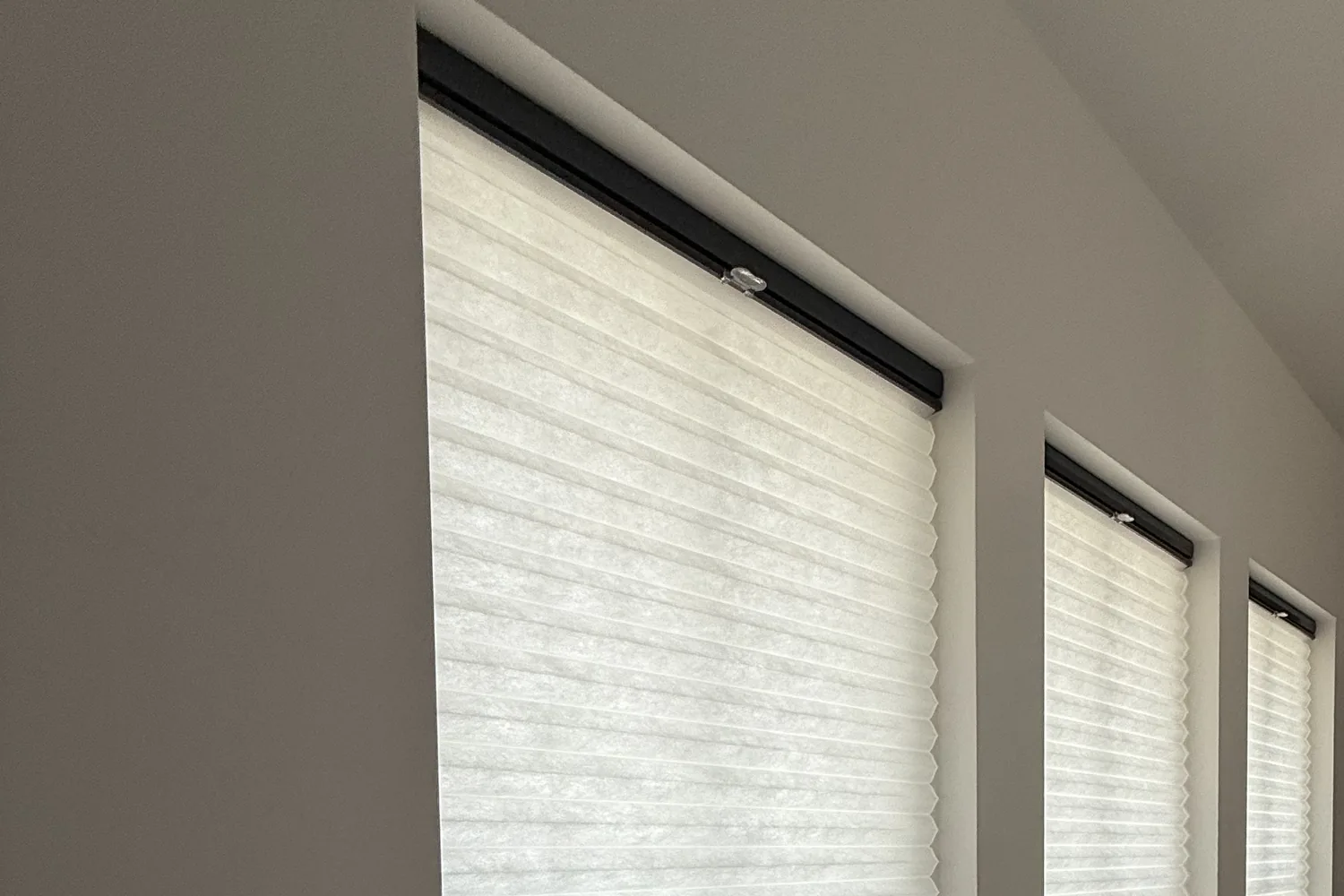 Cellular shades along a sloped-ceiling wall of windows