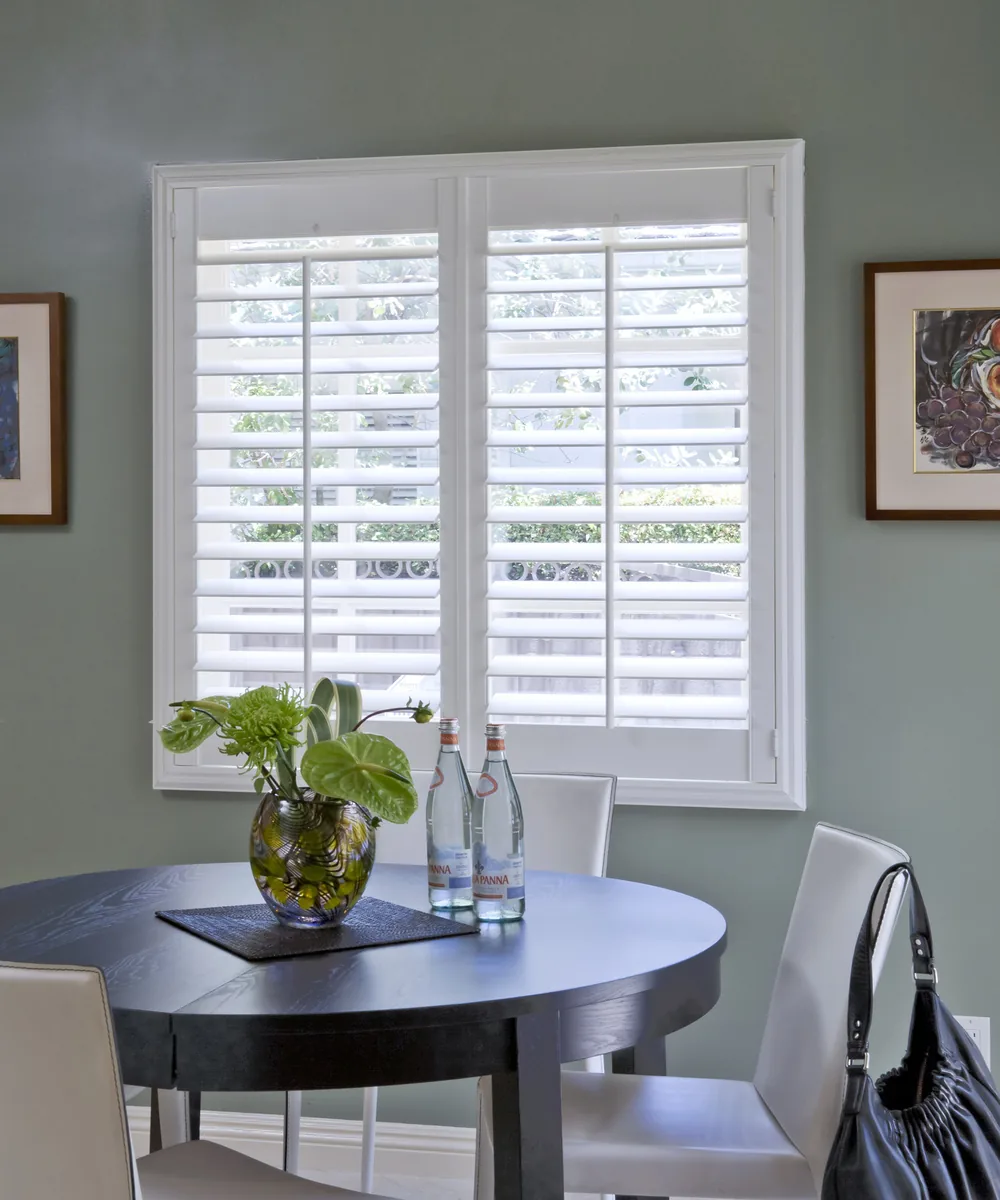 Norman plantation shutters with the louvers tilted halfway, in a dining room